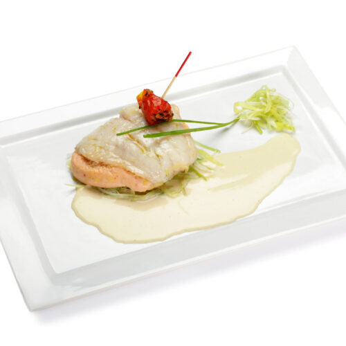Filet de rouget grondin, soufflé de homard, sauce Champagne, présenté sur une assiette en porcelaine blanche rectangulaire