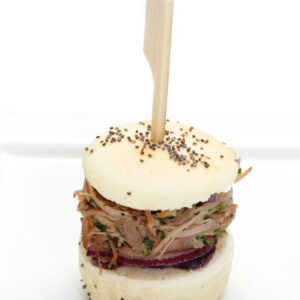Mini-burger Normand de Porlin confit au fumoir présenté avec un pic sur fond blanc