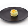 Assiette noire et ronde contenant un maki à la carotte et au cumin. Plateau de Makis Carotte Cumin - 10 pièces