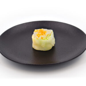 Assiette noire et ronde contenant un maki à la carotte et au cumin. Plateau de Makis Carotte Cumin - 10 pièces