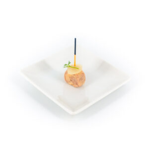 Sucette de foie gras confit et poire, pièce cocktail en pic, présentée sur petite assiette blanche carrée