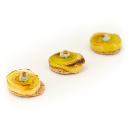 3 prélégantes poireaux et crème de bleu sur sablé sésame sur fond blanc.