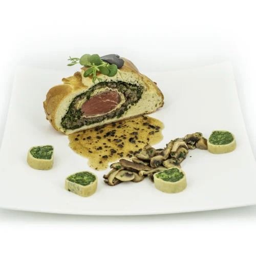 Filet de bœuf brioche façon Wellington dans une assiette sur fond blanc