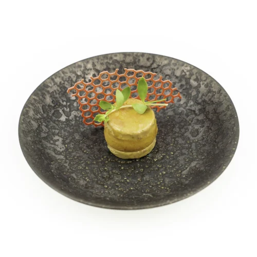 Foie gras pomme tatin dans une assiette noir sur fond blanc