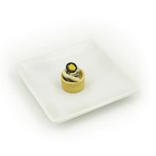 Pintxo houmous et olive dans une assiette sur fond blanc