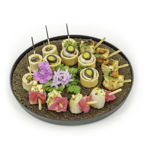 Le plateau "Solstice" - 16 pièces est dressé sur plateau rond, noir, garni de pain brun et de 4 sortes de 16 pièces cocktail colorées