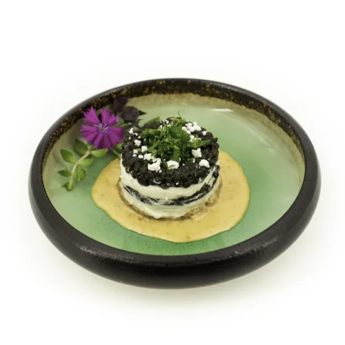 tiramisu lentilles, feta et coriandre fraiche dans une assiette verte sur fond blanc