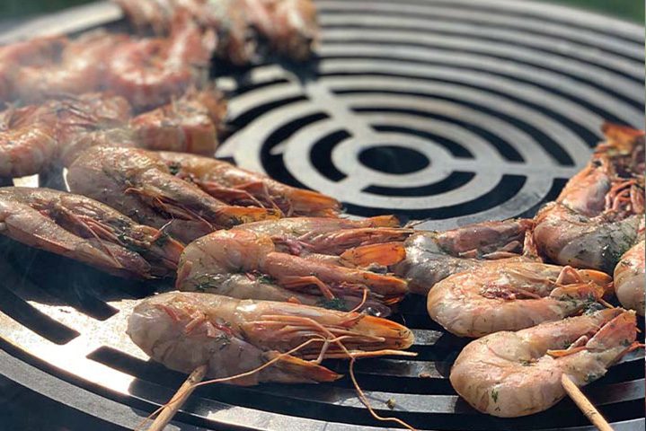 Gambas marinées sur des brochettes en train de griller sur le grill.