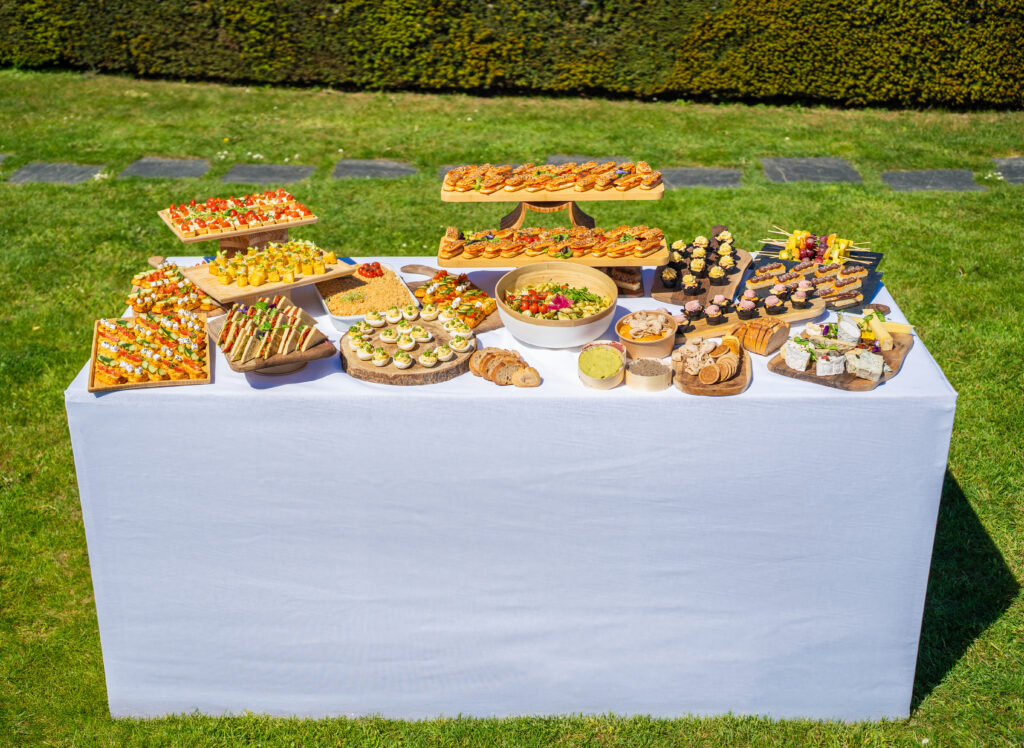 Buffet debout en extérieur sur un table blanche nappée.