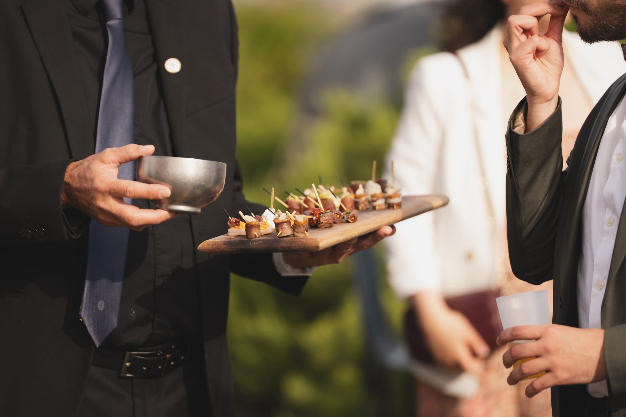 Groupe de trois clients partageant un plateaux en bois de pièces cocktails pendant une réception.
