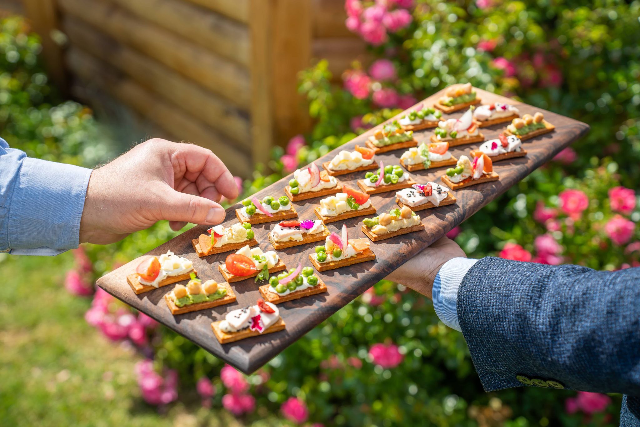 Plateau en bois recouvert de craquantes tenu par un maître d'hôtel.