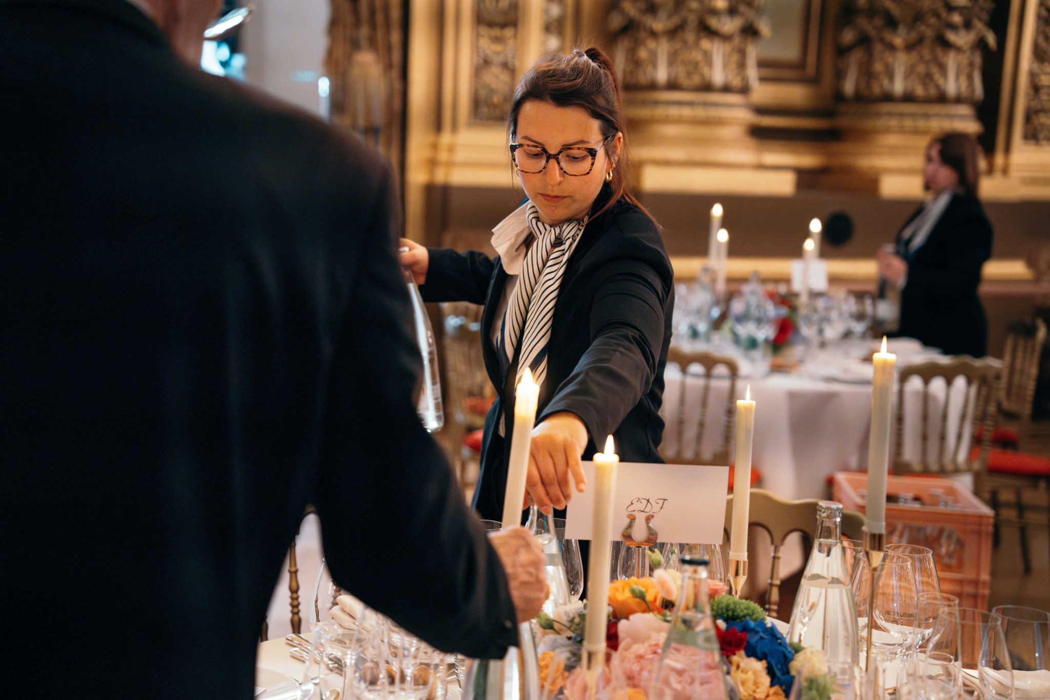 Maître d'hôtel en train de placer une bouteille en verre sur une table pour une réception.