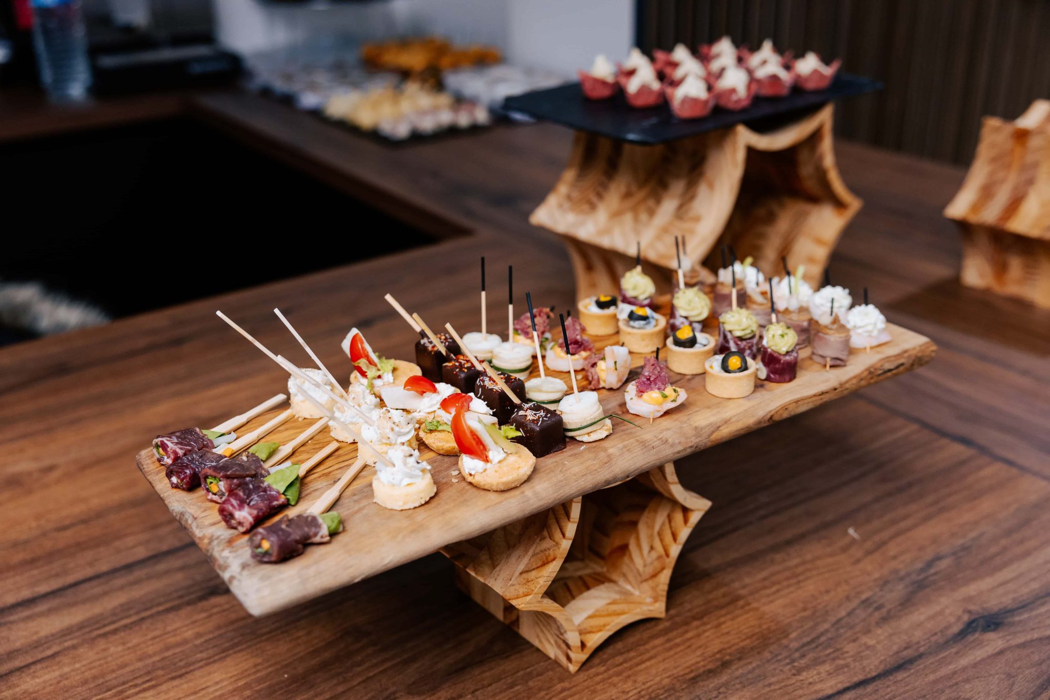 Assortiment de pièces cocktails sur un support en bois.