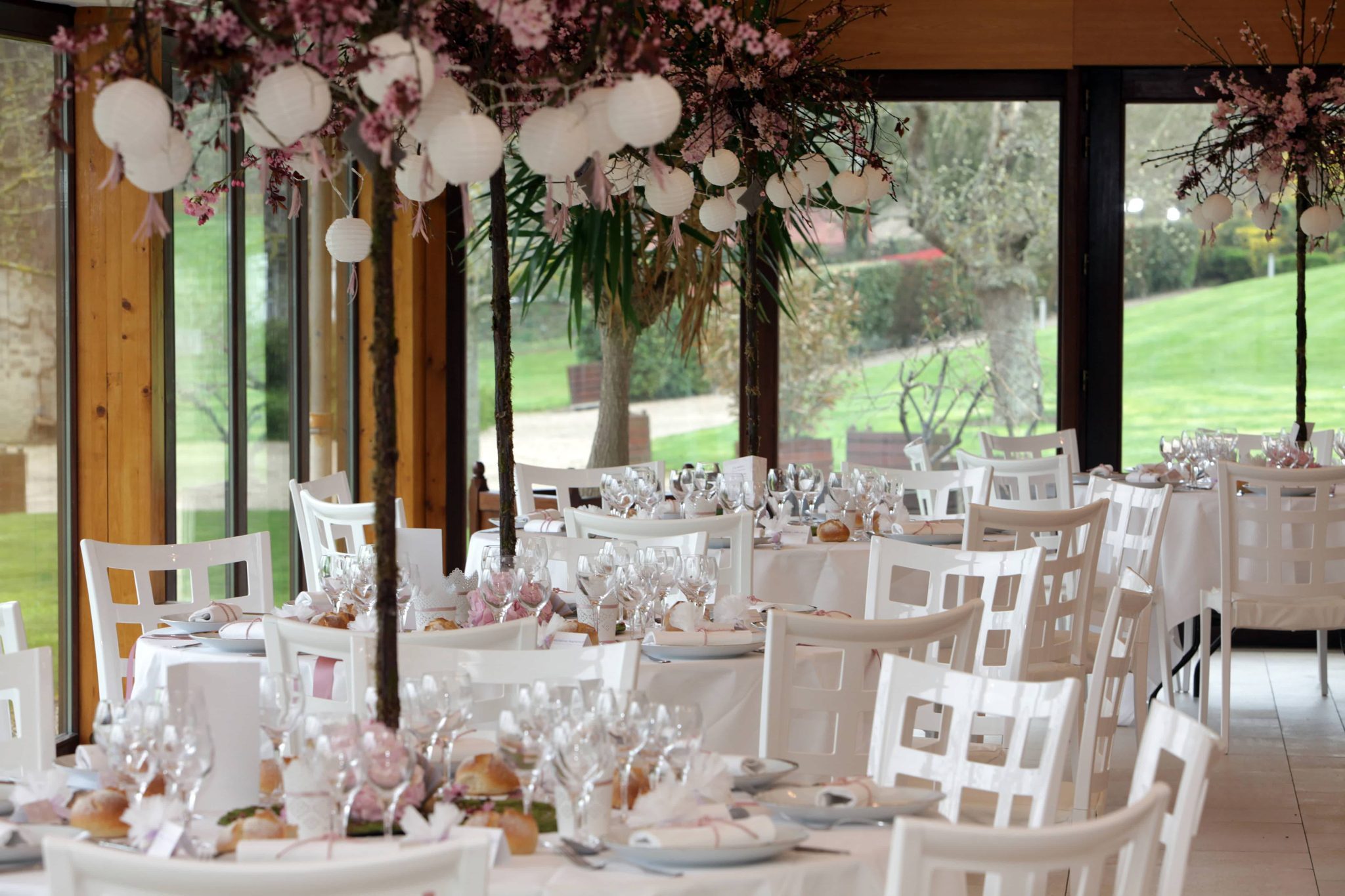 Intérieur du manoir de la chapelle aménagé pour un mariage avec des tables blanches nappées et dressées.